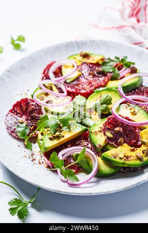 Salade d'oranges sanguines avec avocat, pistaches et oignons rouges, fond blanc, gros plan. Banque D'Images