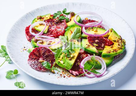 Salade d'oranges sanguines avec avocat, pistaches et oignons rouges, fond blanc, gros plan. Banque D'Images