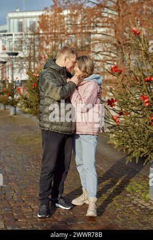 Portrait de jeunes gens attrayants, couple charmant bénéficiant de l'atmosphère chaleureuse sur la foire dans la veille de Noël. Passer du temps ensemble. Concept de national Banque D'Images