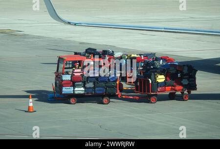 Remorque à bagages de l'aéroport transportant des valises entre le terminal de l'aéroport et l'avion Banque D'Images