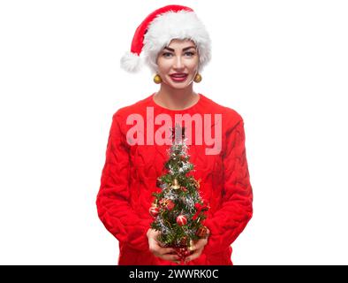 Portrait d'une belle femme dans un chapeau rouge et un pull avec un arbre de Noël sur un thème du nouvel an. Banque D'Images