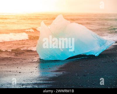 Les icebergs ont été écrasés par les vagues de la mer sur la plage noire au lever du soleil près du lac glacier de Jokulsarlon, en Islande. Banque D'Images