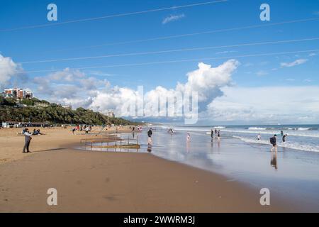 Bournemouth, Royaume-Uni - 2 août 2023 : les gens sur le sable humide de la plage est de Bournemouth avec un grand nuage en arrière-plan. Banque D'Images