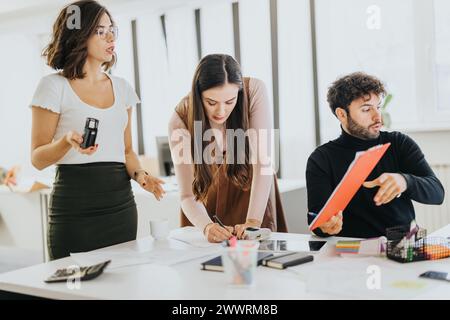 Trois professionnels se sont engagés dans une discussion dans un bureau moderne, avec une femme présentant des idées à ses collègues ciblés. Banque D'Images