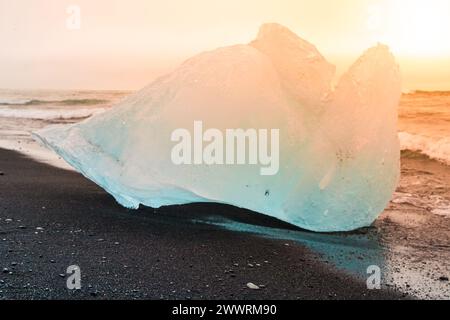 Les icebergs ont été écrasés par les vagues de la mer sur la plage noire au lever du soleil près du lac glacier de Jokulsarlon, en Islande. Banque D'Images