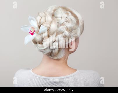 Belle fille aux cheveux blonds, coiffeuse tisse un gros plan de tresse, dans un salon de beauté. Soins capillaires professionnels et création de coiffures. Banque D'Images