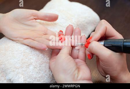 Le maître de la manucure scie et attache une forme d'ongle pendant la procédure d'extensions d'ongles avec gel dans le salon de beauté. Soins professionnels pour Banque D'Images