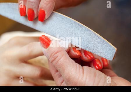 Le maître de la manucure scie et attache une forme d'ongle pendant la procédure d'extensions d'ongles avec gel dans le salon de beauté. Soins professionnels pour Banque D'Images