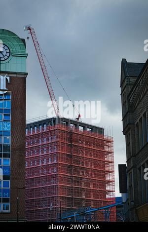 Chantier de construction urbaine avec grue et échafaudage contre un ciel nuageux, mettant en valeur le développement de la ville à Leeds, Royaume-Uni. Banque D'Images