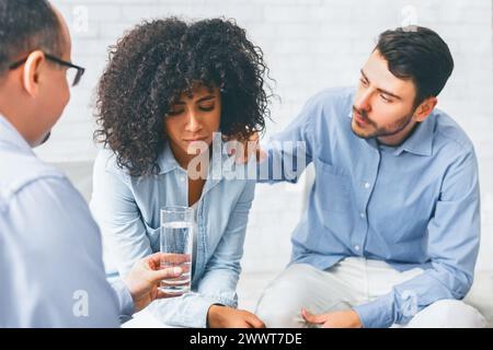 Membres de la communauté Rehab soutenant une femme afro bouleversée à la séance de thérapie Banque D'Images