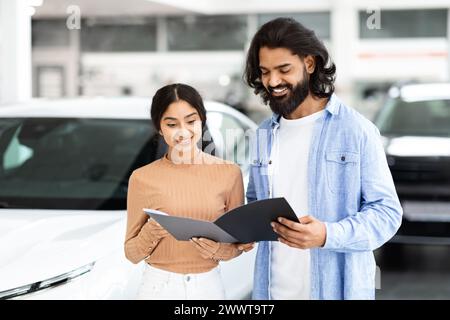 Couple examinant une brochure de voiture dans une concession Banque D'Images