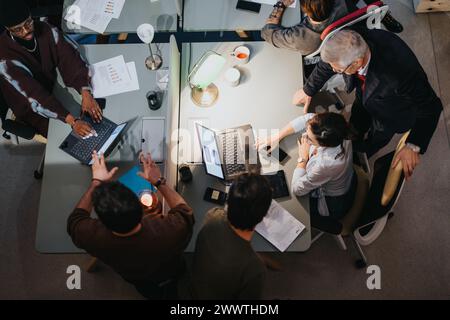 Vue aérienne de collègues multigénérationnels collaborant dans un bureau moderne et bien éclairé lors d'une réunion importante. Banque D'Images