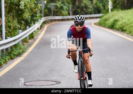 jeune femme asiatique cycliste femme chevauchant le vélo à l'extérieur sur la route rurale Banque D'Images