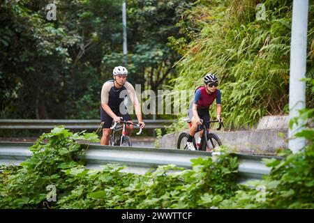 jeunes cyclistes de couple asiatique faisant du vélo sur la route rurale Banque D'Images