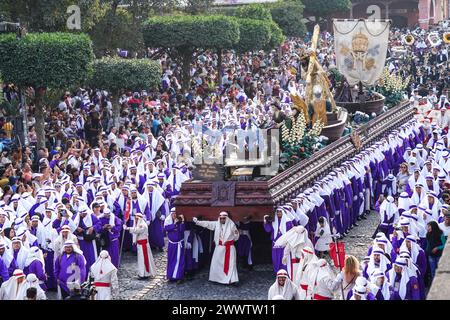 Antigua, Guatemala. 24 mars 2024. Les pénitents catholiques entourent le massif flotteur processionnel alors qu'il se déplace sur la place centrale pendant la procession de 20 heures du dimanche des Rameaux la Reseña marquant le début de la semaine Sainte, le 24 mars 2024 à Antigua, au Guatemala. Les processions opulentes, les algèbres détaillées et les traditions séculaires attirent plus d'un million de personnes dans l'ancienne capitale. Crédit : Richard Ellis/Richard Ellis/Alamy Live News Banque D'Images