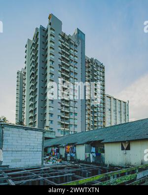 Une photo contrastant un immeuble de bureaux moderne de grande hauteur avec une petite cabane altérée au premier plan. Cette image met en lumière les thèmes du développement urbain Banque D'Images