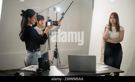 Une photographe asiatique professionnelle et cool prenant des photos d'un mannequin dans le studio avec un équipement d'éclairage professionnel. Une équipe de photos de mode Banque D'Images