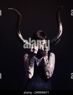 Cornes, démon et femme avec tatouage en portrait pour magie noire, horreur ou esthétique artistique en studio. Cauchemar créatif, culture d'halloween et Banque D'Images