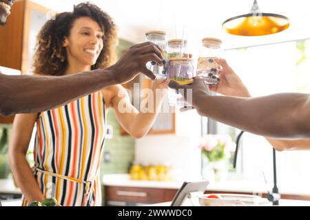Un couple diversifié toast avec des smoothies sains dans une cuisine ensoleillée Banque D'Images