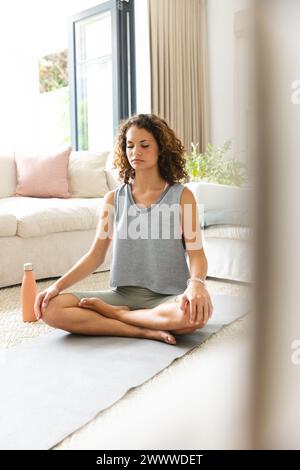 Une jeune femme caucasienne médite dans un environnement familial serein Banque D'Images