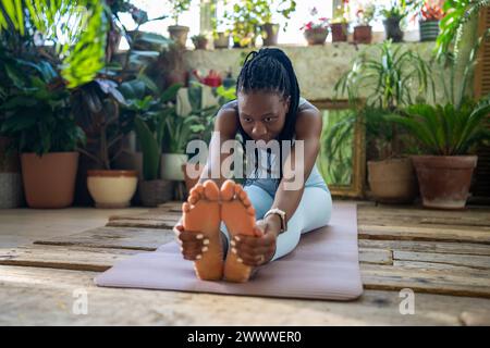 Axé sur la femme noire de corps sain faisant des exercices d'étirement relaxant les muscles après la remise en forme à la maison. Banque D'Images