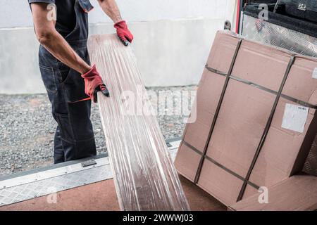 Homme en tenue de travail déchargeant des boîtes en carton d'un fourgon de livraison, mettant l'accent sur la logistique, l'efficacité et l'industrie des services de livraison. Banque D'Images