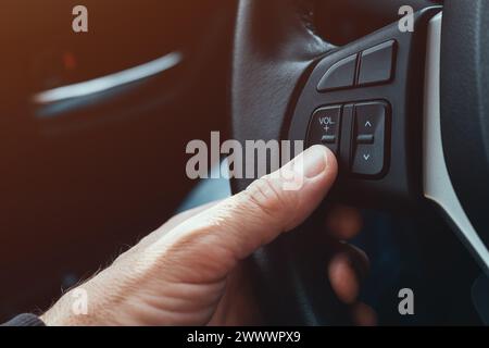 Conducteur appuyant sur le bouton de réduction du volume sur le volant de la voiture, mise au point sélective Banque D'Images