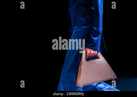 Femme portant une tenue bleue et tenant un élégant sac à main minimaliste blanc Banque D'Images