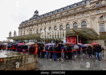 Paris, France. 26 mars 2024. Les visiteurs font la queue, sous la pluie, en attendant d’entrer au Musée d’Orsay, Musée d’Orsay, le premier jour de l’exposition Paris 1874, inventer l’impressionnisme, célébrant les 150 ans de la première exposition impressionniste ouverte à Paris le 15 avril 1874. Banque D'Images