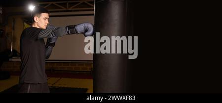 Boxeur masculin poinçonnage dans une séance d'entraînement de boxe féroce, mettant en valeur la technique de boxe thaïlandaise. Banque D'Images