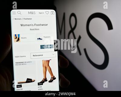 Personne tenant le téléphone portable avec la page Web de la société de détail britannique Marks et Spencer Group plc avec le logo. Concentrez-vous sur le centre de l'écran du téléphone. Banque D'Images