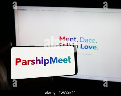 Personne tenant un smartphone avec le logo de la société allemande de rencontres en ligne ParshipMeet Holding GmbH en face du site. Concentrez-vous sur l'affichage du téléphone. Banque D'Images