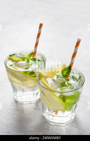Deux verres de limonade ornés de glace, de tranches de citron et de feuilles de menthe fraîche, évoquant une ambiance estivale rafraîchissante. Mise en valeur des boissons rafraîchissantes et des Seaso Banque D'Images