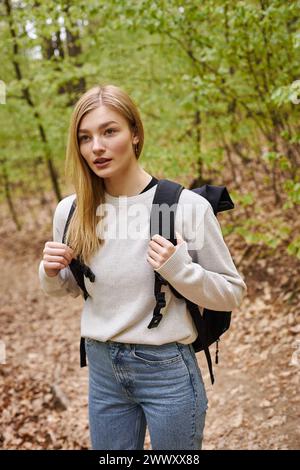 Portrait de jeune voyageuse blonde avec sac à dos randonnée dans la forêt d'automne et debout sur le chemin Banque D'Images
