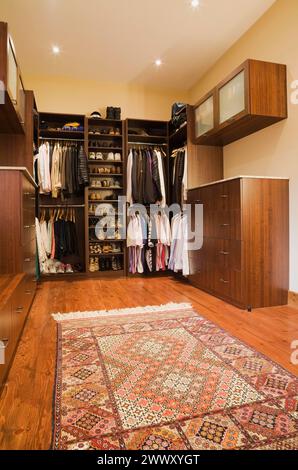 Dressing avec vêtements assortis pour hommes et femmes et tapis en extension à l'intérieur d'une luxueuse maison de chalet en rondins, Québec, Canada Banque D'Images