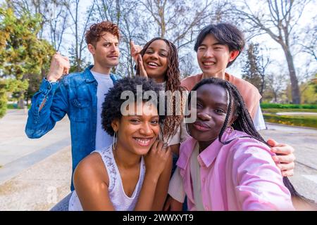 Perspective personnelle d'un groupe de jeunes amis heureux et divers prenant un selfie de groupe dans un parc Banque D'Images
