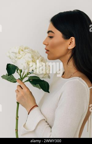 Jeune belle femme avec des fleurs près du visage. Concept de traitement de beauté. Soins de la peau. Jolie femelle avec la santé, peau fraîche du corps. Banque D'Images