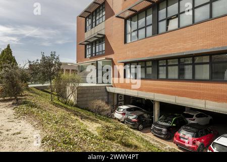 immeuble de bureaux avec murs de briques marron clair combinés avec des fenêtres en métal noir, parking au rez-de-chaussée dans une zone industrielle Banque D'Images