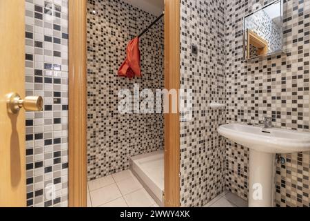 salle de bains avec petit lavabo en porcelaine, miroir au-dessus, murs en gresite, douche séparée Banque D'Images