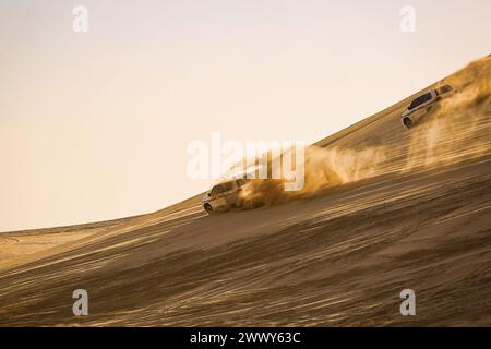 Un véhicule 4RM sportif roulant à grande vitesse dans le sable du désert. Pulvérisation de sable autour de la voiture. Seuls les experts peuvent conduire et profiter du désert. Banque D'Images