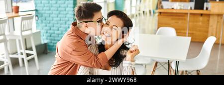 Fils aimant avec le syndrome de Down embrassant sa mère heureuse dans un café, bannière horizontale Banque D'Images