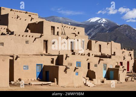 NM00695-00....NOUVEAU MEXIQUE - Maison du Nord, avec portes et échelle, Taos Pueblo terre tribale. Les montagnes Taos de la chaîne de Sangre de Cristo sont dans la BA Banque D'Images