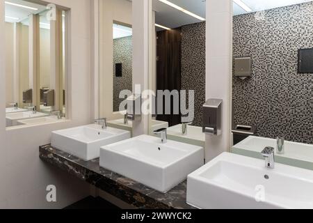 Intérieur de lavabo de toilettes publiques avec lavabo pour le lavage des mains et miroir. Intérieur public contemporain de salle de bains avec lavabo robinet lin Banque D'Images