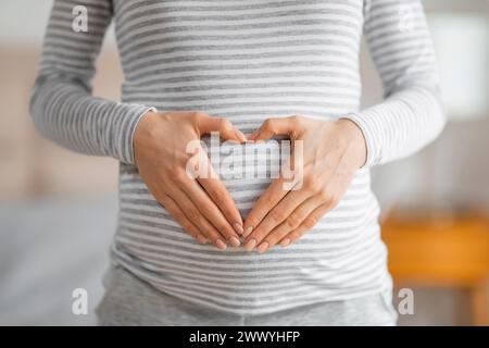 Femme enceinte formant une forme de coeur sur le ventre Banque D'Images