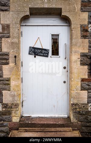 Porte gothique avec une porte boisée blanche et un panneau bilingue des heures d'ouverture en gallois et en anglais. Cardiff, pays de Galles, Royaume-Uni Banque D'Images