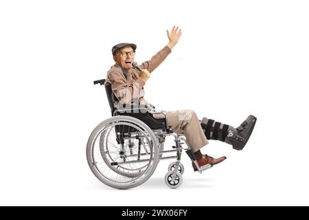 Homme âgé joyeux avec une jambe cassée dans un fauteuil roulant tenant un microphone et chantant isolé sur fond blanc Banque D'Images