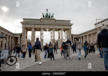 Berlin, Allemagne. 26 mars 2024. Les touristes se promènent sous le regard stoïque de la Quadriga au sommet de la porte de Brandebourg, l'un des monuments les plus emblématiques de Berlin. Le monument néoclassique, qui a été témoin de la grandeur et du tumulte de la ville, sert de toile de fond poignante aux moments ordinaires des citadins et des visiteurs. La porte, autrefois symbole de division pendant la guerre froide, incarne aujourd'hui l'unité et la paix dans une ville riche en histoire. (Crédit image : © Michael Kuenne/PRESSCOV via ZUMA Press Wire) USAGE ÉDITORIAL SEULEMENT! Non destiné à UN USAGE commercial ! Banque D'Images