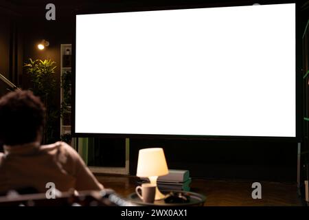 Homme regardant la compétition de football en direct sur écran isolé ultra large Smart TV, acclamant l'équipe préférée. Fan de sport sur le canapé devant la maquette d'écran de télévision regardant le football Banque D'Images