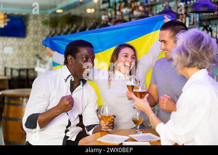 Heureux fans célébrant la victoire de l'équipe ukrainienne au bar Banque D'Images