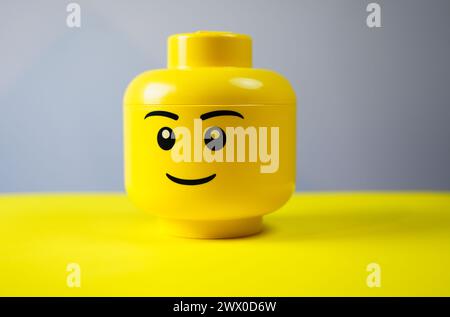 Boîte jaune Lego Head avec fond gris. Banque D'Images